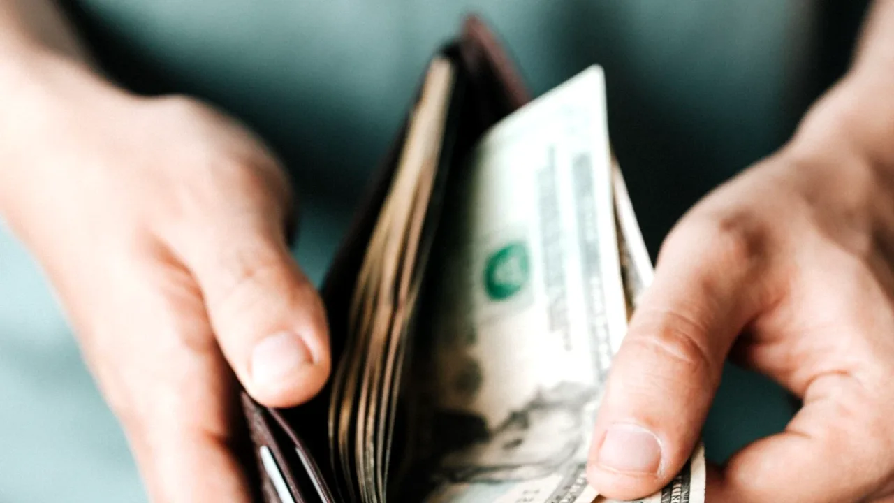 Elde tutulan deri cüzdandan banknot çıkaran kişi